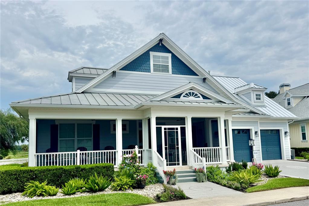 A light blue house with a metal roof, two garage doors, and a front porch — 1040 COTTAGE DRIVE, THE VILLAGES, FL