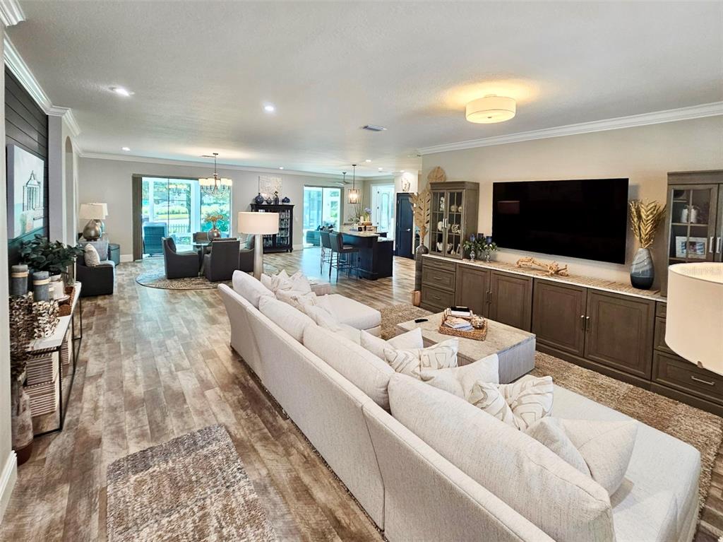 A dining room features a round table, gray upholstered chairs, a sideboard, and wood-look flooring — 1040 COTTAGE DRIVE, THE VILLAGES, FL