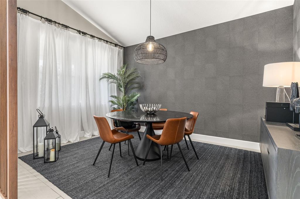 A dining room features a round black table, leather chairs, and a textured gray wall — 14321 WABASSO LOOP, WINTER GARDEN, FL