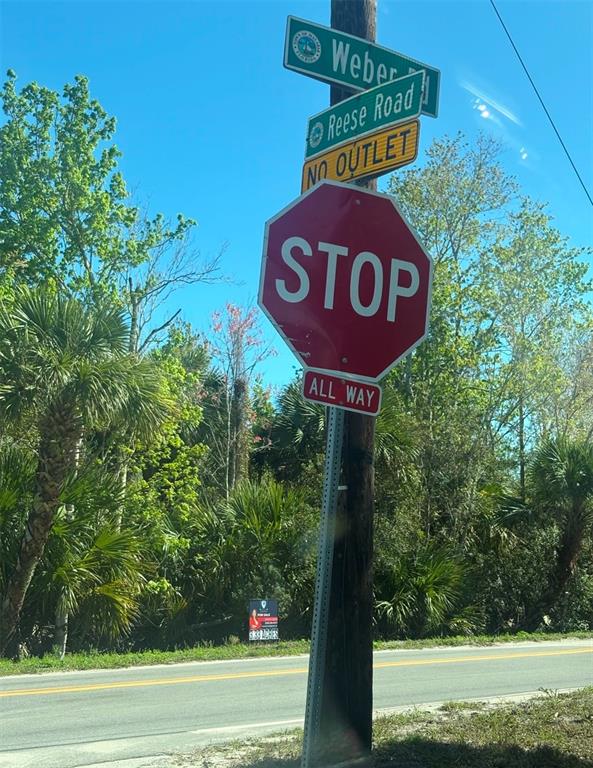 A stop sign and street signs for Weber and Reese Road stand beside a road — 3305 WEBER ROAD, GRANT VALKARIA, FL
