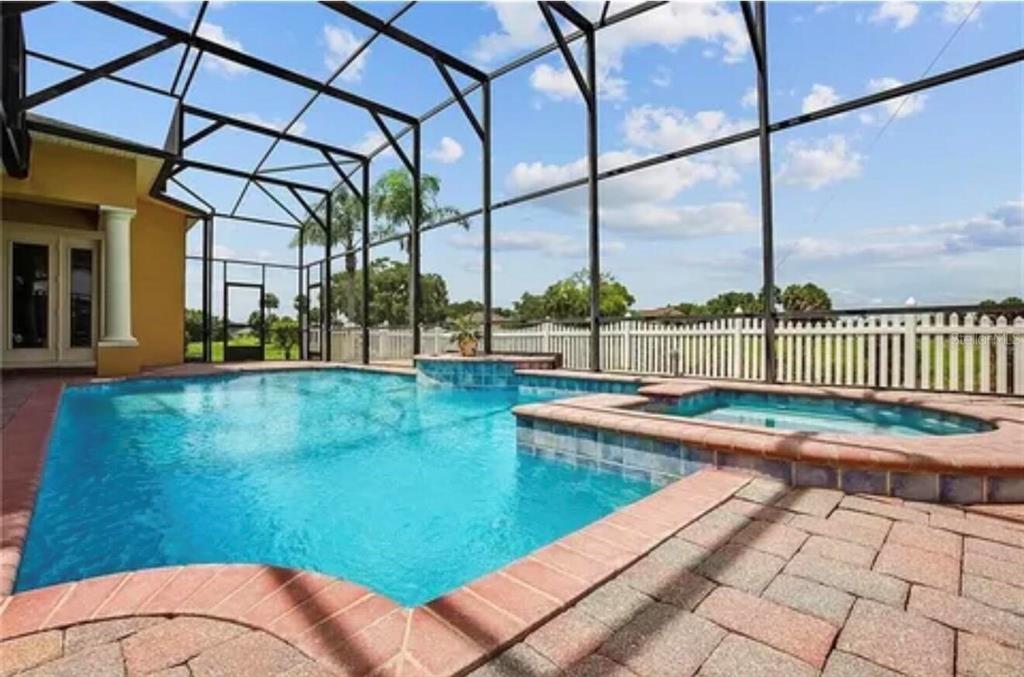 A yellow single-story house with a three-car garage and a paved driveway under a blue sky — 2120 BUNKER VIEW COURT, KISSIMMEE, FL