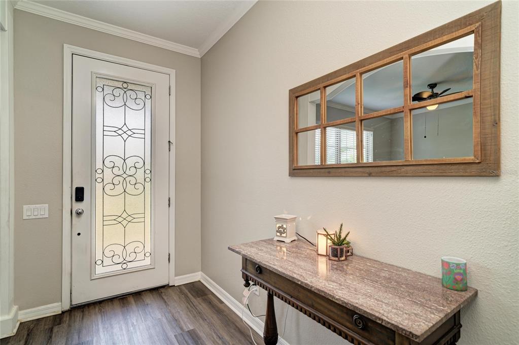 An entryway features a white front door with decorative glass, a console table, and a mirror — 6031 100TH AVENUE E, PARRISH, FL