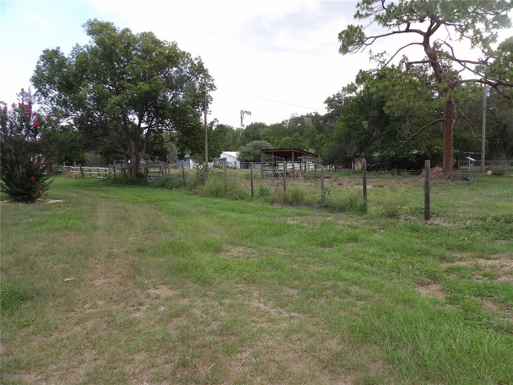 A grassy field with a wire fence, trees, and a small open-sided shelter — 18211 OAKLAWN, SPRING HILL, FL