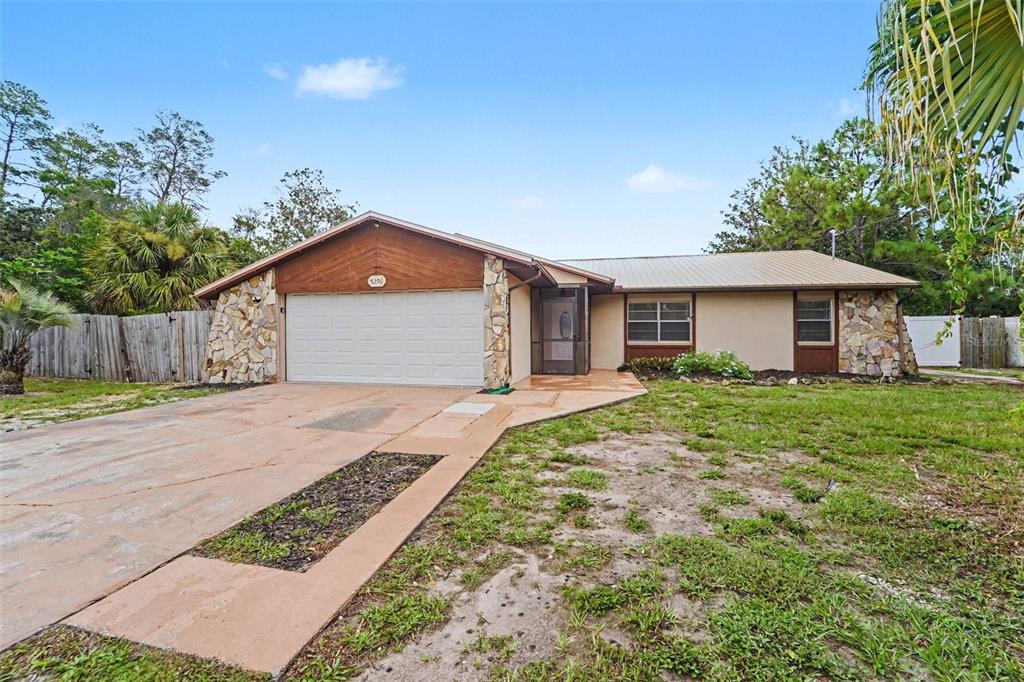 A single-story house with a two-car garage, stone accents, and a metal roof — 5296 FREEPORT DRIVE, SPRING HILL, FL