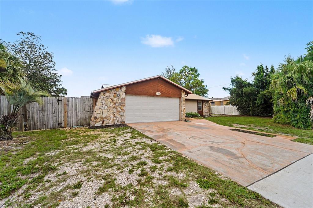 A single-story house features a stone-accented facade, a two-car garage, and a concrete driveway — 5296 FREEPORT DRIVE, SPRING HILL, FL