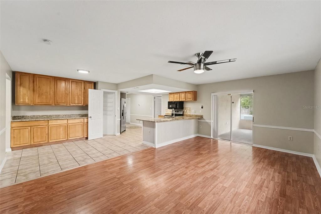 An open-concept living area features wood-look flooring, a kitchen with light wood cabinets, and tile — 5296 FREEPORT DRIVE, SPRING HILL, FL