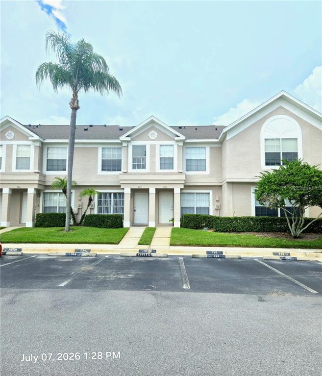A two-story residential building features tan siding, multiple windows, and a palm tree out front — 734 KENSINGTON LAKE CIR UNIT BRANDON, BRANDON, FL