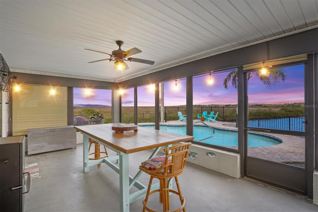 A covered patio features a wooden dining table, a ceiling fan, and a swimming pool — 15722 DONZI DRIVE, HUDSON, FL