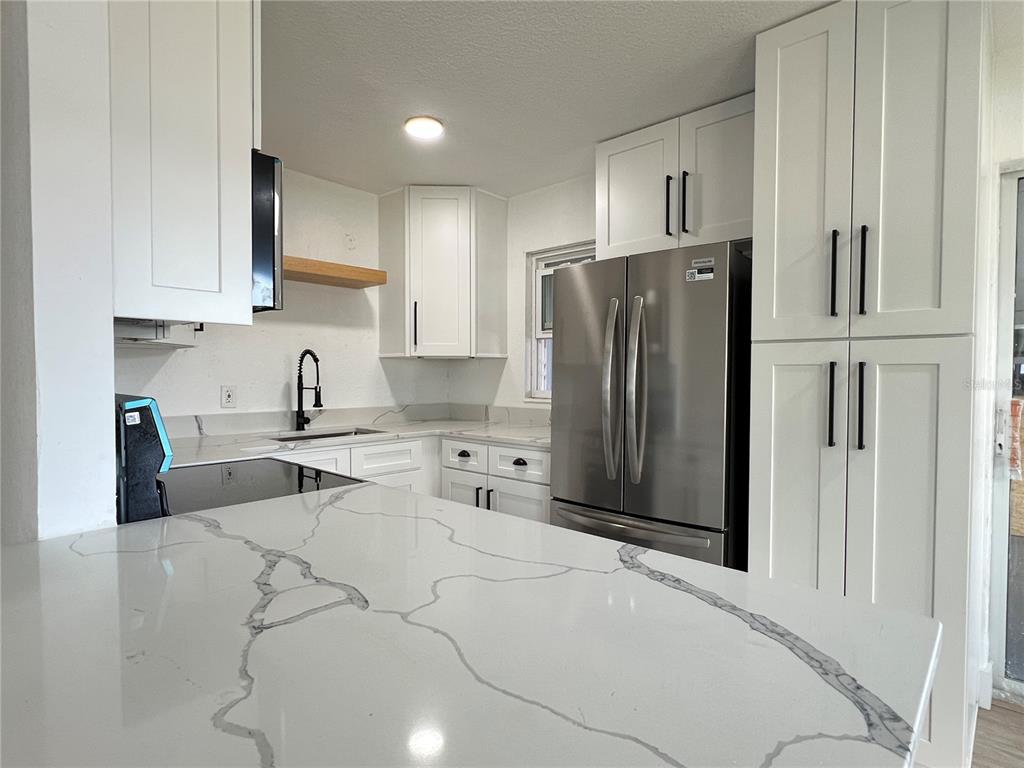 A kitchen features white cabinets, stainless steel appliances, and a white quartz countertop with veining — 2578 COVENTRY ROAD, MELBOURNE, FL