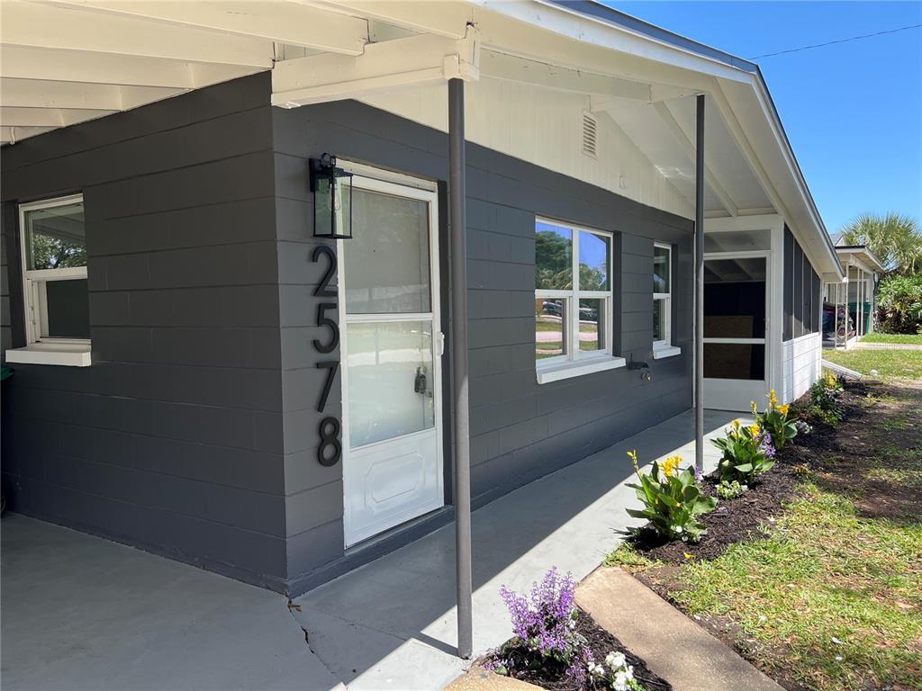 The exterior of a gray concrete block house features a covered porch and front door — 2578 COVENTRY ROAD, MELBOURNE, FL