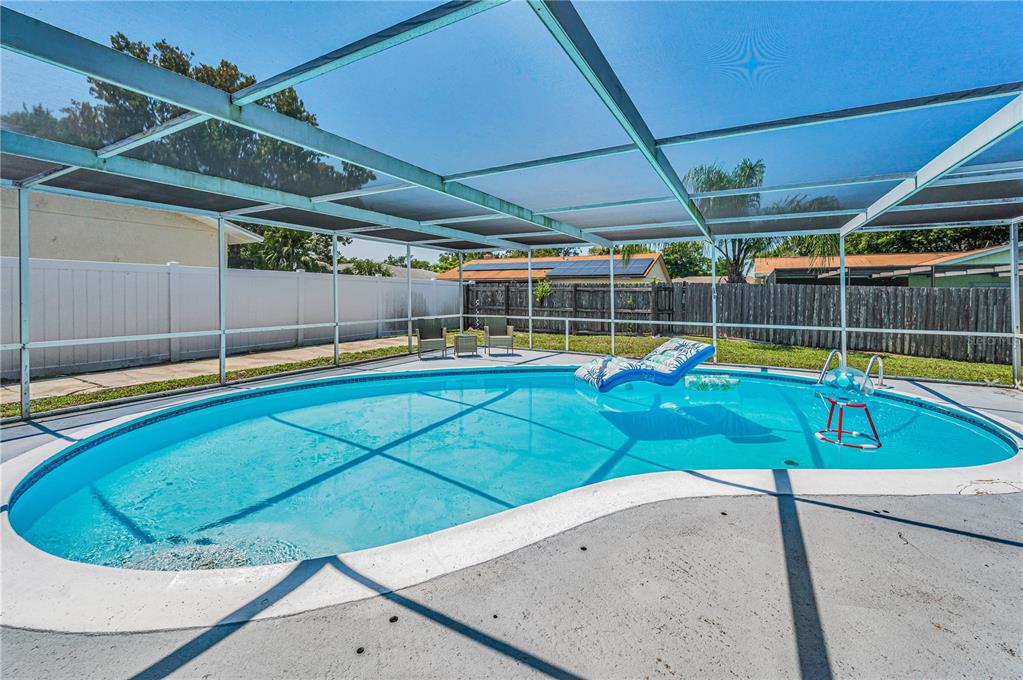 A single-story house with a beige stucco exterior, a brown roof, and a front garage — 11121 PEPPERTREE LANE, PORT RICHEY, FL
