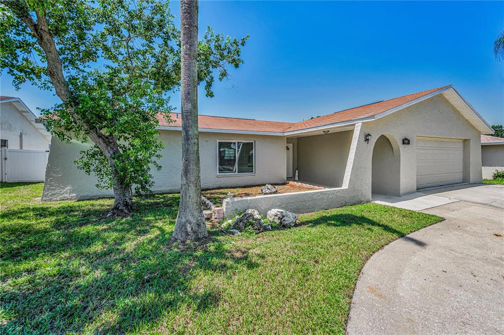 A single-story house with a beige stucco exterior, a two-car garage, and a concrete driveway — 11121 PEPPERTREE LANE, PORT RICHEY, FL
