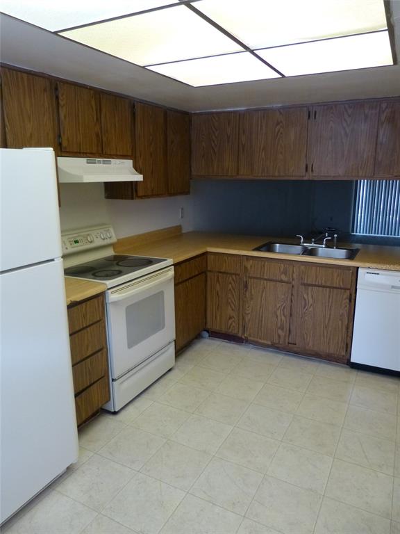 A kitchen features wood cabinets, white appliances, a double sink, and light-colored tile flooring — 12125 NAPIERS CIRCLE, ORLANDO, FL