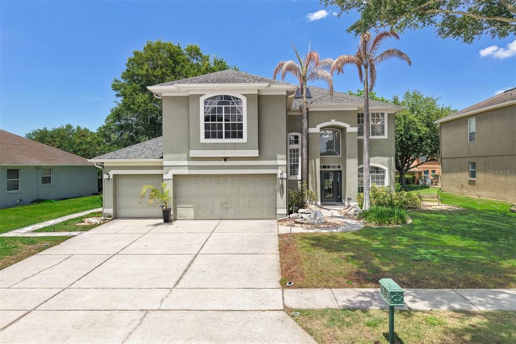 A two-story house with a three-car garage, palm trees, and a concrete driveway — 816 LANCER CIRCLE, OCOEE, FL