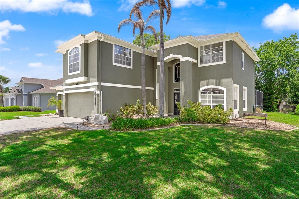 A two-story house with olive green stucco siding, a two-car garage, and palm trees — 816 LANCER CIRCLE, OCOEE, FL