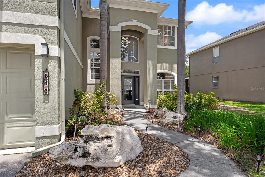 The exterior of a two-story house features a stone-accented walkway and a large boulder — 816 LANCER CIRCLE, OCOEE, FL