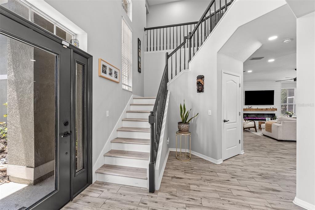 An entryway features a staircase with black railings, light wood-look flooring, and a white door — 816 LANCER CIRCLE, OCOEE, FL