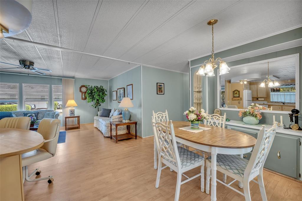 A dining area and living room with light blue walls, wood-look flooring, and white furniture — 53 KONO CIRCLE, LEESBURG, FL