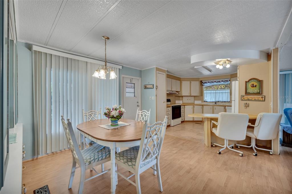 A dining area with a wooden table and chairs adjacent to an open-concept kitchen — 53 KONO CIRCLE, LEESBURG, FL
