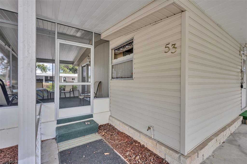 The exterior of a mobile home features light beige siding, a screened porch, and number 53 — 53 KONO CIRCLE, LEESBURG, FL