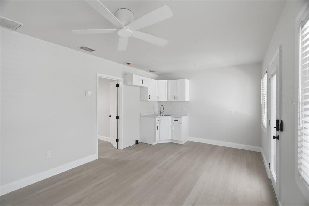 A room with light wood-look flooring, white walls, a ceiling fan, and a small kitchenette — 3101 BEACH BOULEVARD S UNIT 1-5, GULFPORT, FL