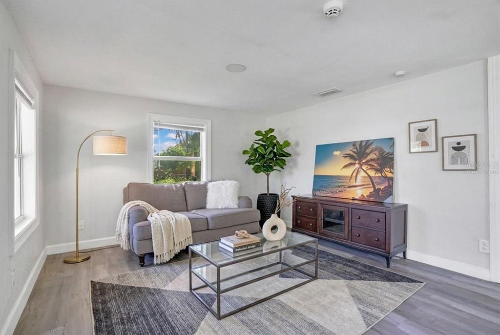 A living room with a gray sofa, glass coffee table, and a dark wood media console — 2012 E HARDING STREET, ORLANDO, FL