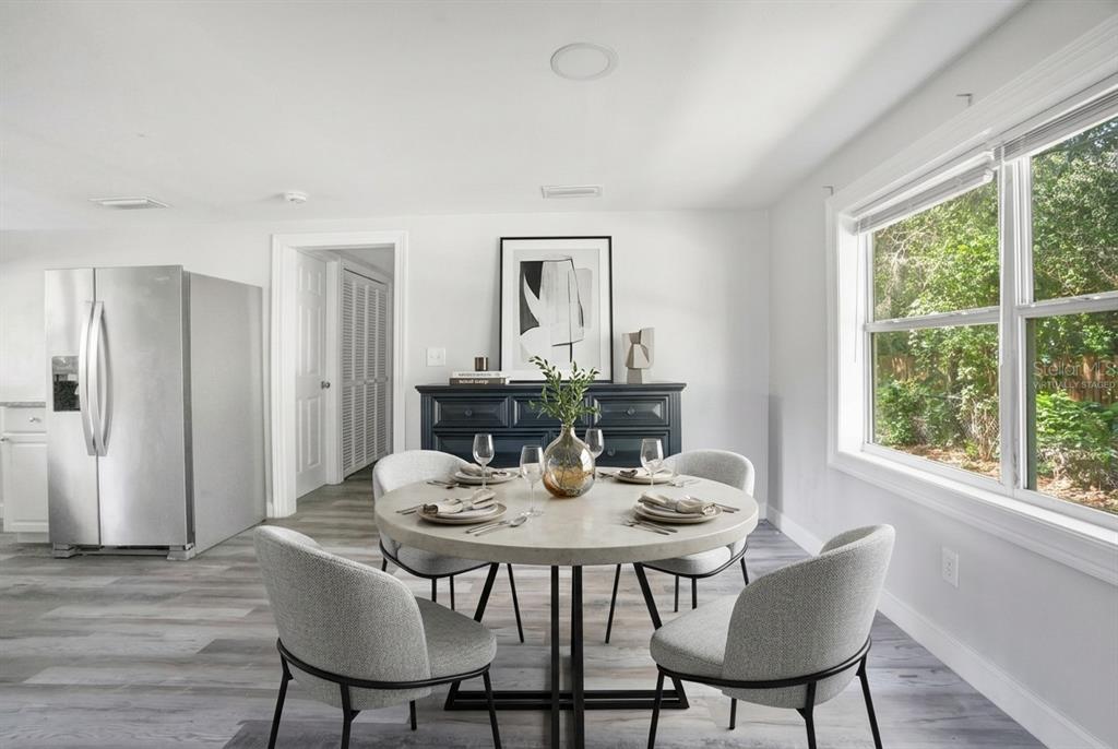 A dining area features a round concrete table, four gray chairs, and a dark sideboard — 2012 E HARDING STREET, ORLANDO, FL