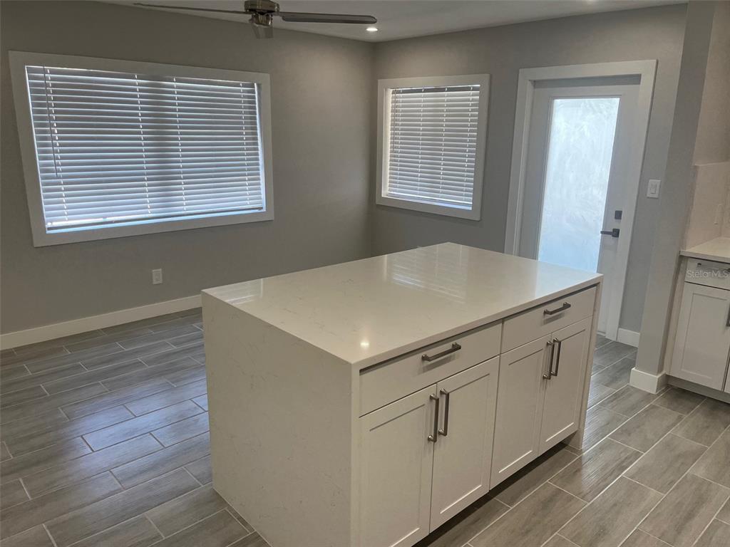 A kitchen island with white cabinets and a quartz countertop sits on gray tile flooring — 1605 PASS A GRILLE WAY UNIT 1, ST PETE BEACH, FL