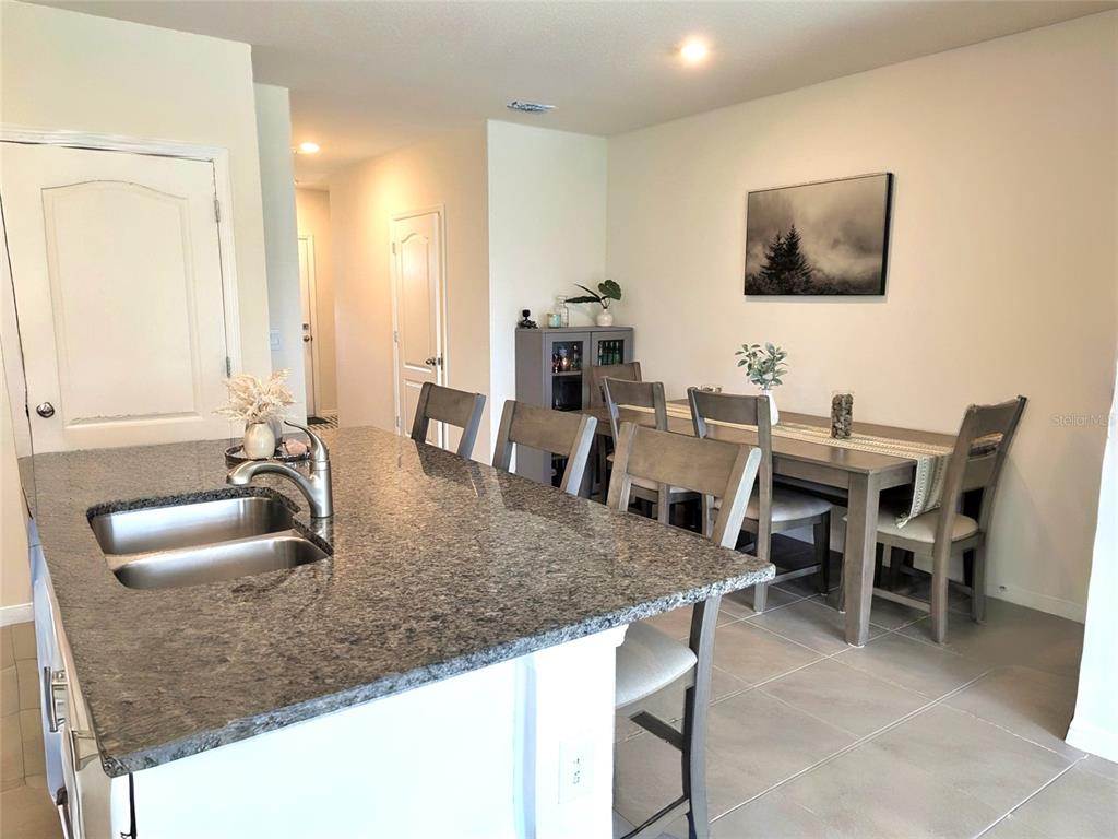 A kitchen island with a granite countertop sits in front of a dining area — 60 BELLA LAGO CIRCLE, PORT ORANGE, FL