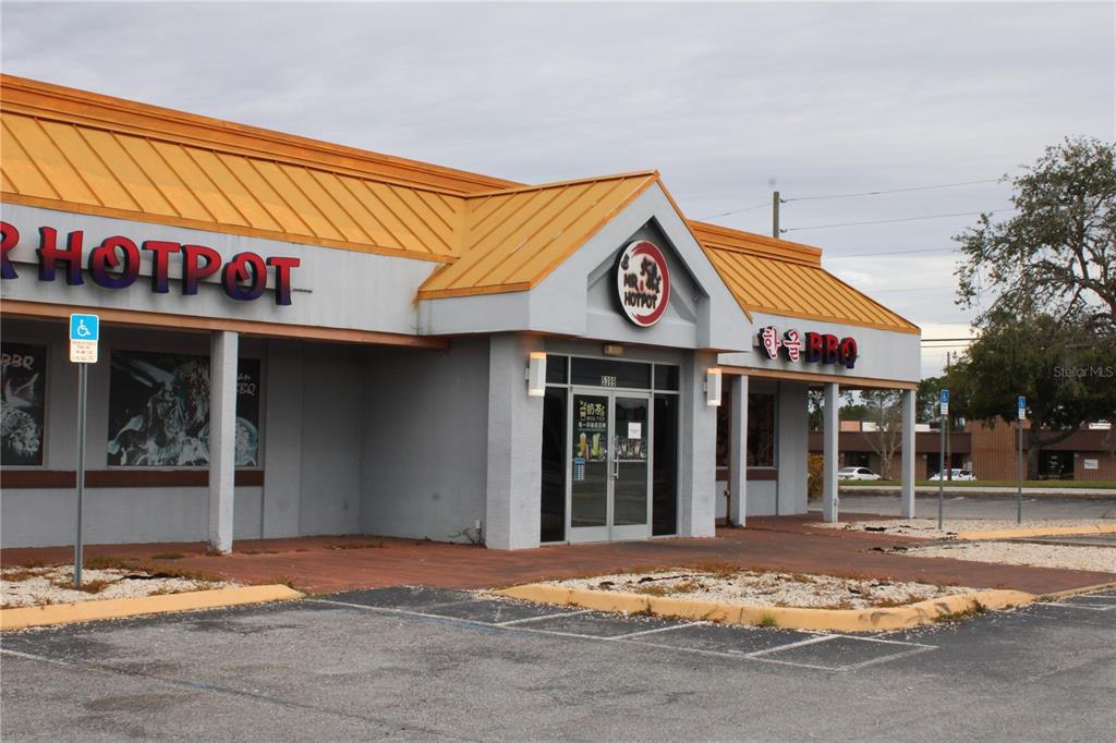 The exterior of a restaurant building features a yellow metal roof and grey walls — COMMERCIAL WAY, SPRING HILL, FL