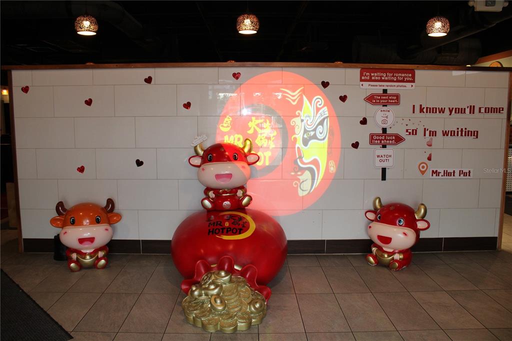 A restaurant interior features three cartoon bull statues and a wall with decorative signage — COMMERCIAL WAY, SPRING HILL, FL