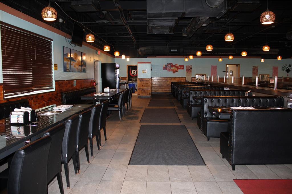 A restaurant dining room features black booths, tables, tiled floors, and hanging pendant lights — COMMERCIAL WAY, SPRING HILL, FL
