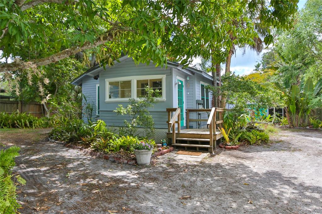 A small, light blue cottage with a wooden porch sits on a sandy lot — 708 42ND STREET, SARASOTA, FL