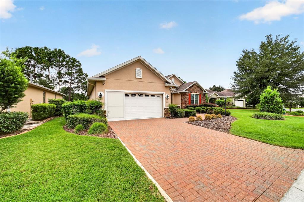 A single-story house with a brick driveway, tan stucco exterior, and a two-car garage — 8815 SW 83RD COURT ROAD, OCALA, FL