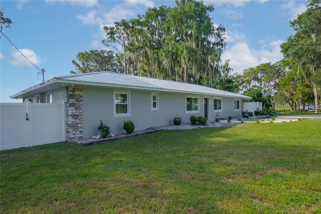 A single-story house with a gray exterior, stone accents, and a white metal roof — 221 S HUNTING LODGE DRIVE, INVERNESS, FL