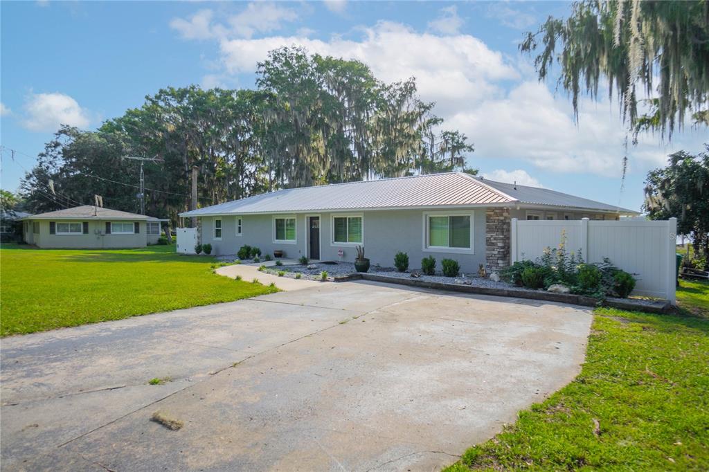 A single-story gray house with a metal roof and a concrete driveway — 221 S HUNTING LODGE DRIVE, INVERNESS, FL