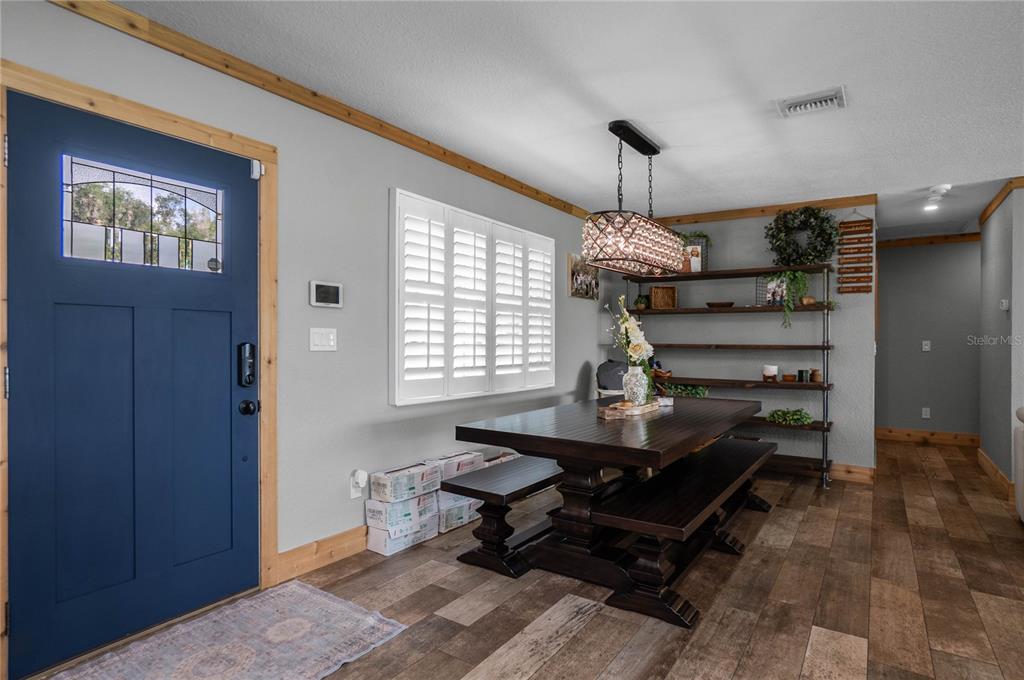 A dining room features a dark wood table, benches, a crystal chandelier, and blue door — 221 S HUNTING LODGE DRIVE, INVERNESS, FL
