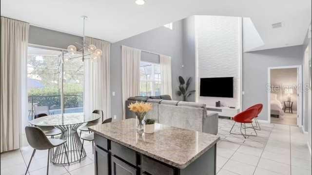 A kitchen island overlooks a living room with a high ceiling, fireplace, and dining area — 4352 ACORN COURT, DAVENPORT, FL