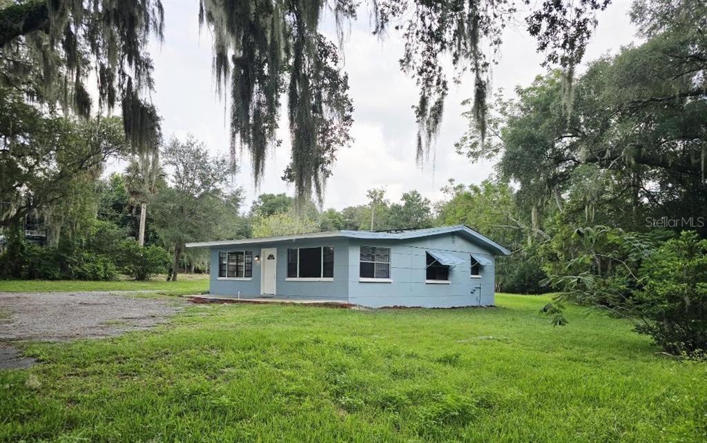 A single-story blue house with a flat roof sits on a grassy lot with trees — 234 E LADY LAKE BOULEVARD, LADY LAKE, FL