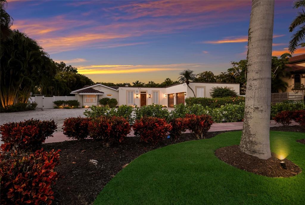 A single-story house with a gravel driveway and landscaped yard at sunset — 103 FILLMORE DRIVE, SARASOTA, FL