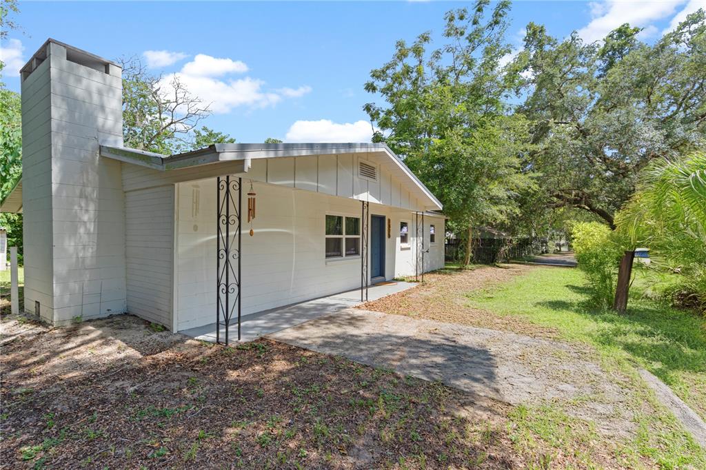 A white single-story house with a prominent chimney and a covered front porch — 1825 SE 47TH TERRACE, GAINESVILLE, FL