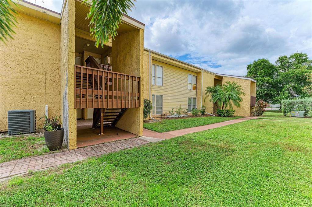 A two-story yellow apartment building with a wooden staircase and a brick walkway — 3471 CLARK ROAD UNIT 169, SARASOTA, FL