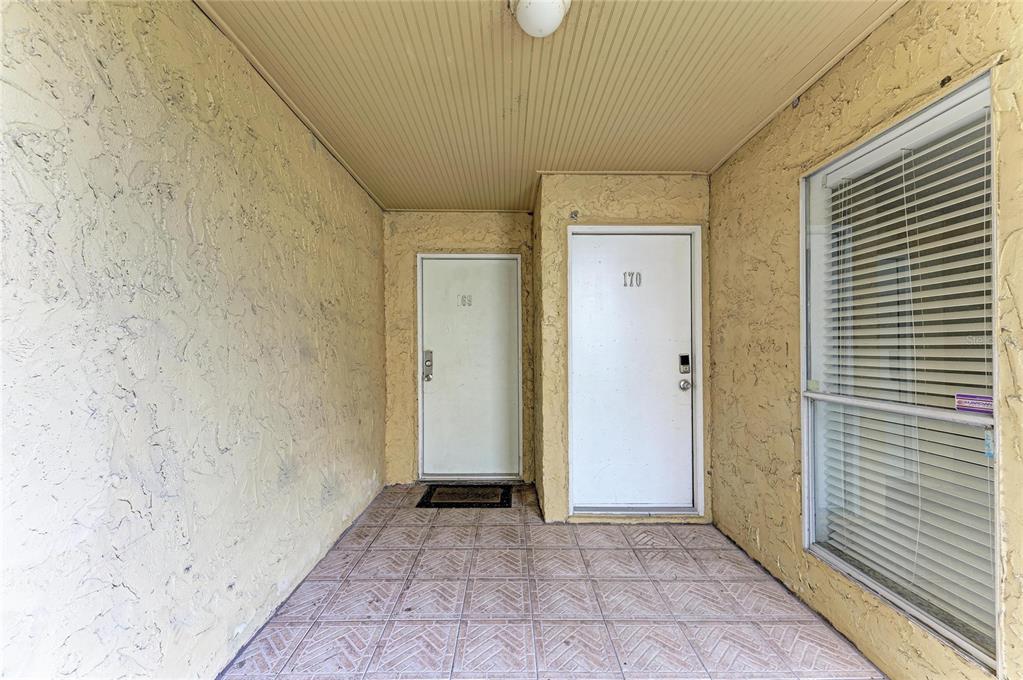 An exterior entryway shows two white doors numbered 169 and 170 with tiled flooring — 3471 CLARK ROAD UNIT 169, SARASOTA, FL