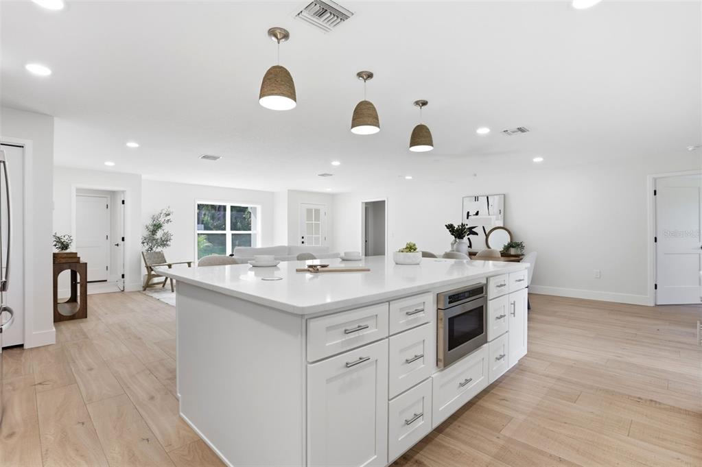 A modern kitchen features a large white island with a built-in microwave and pendant lighting — 39251 COUNTY ROAD 439, UMATILLA, FL