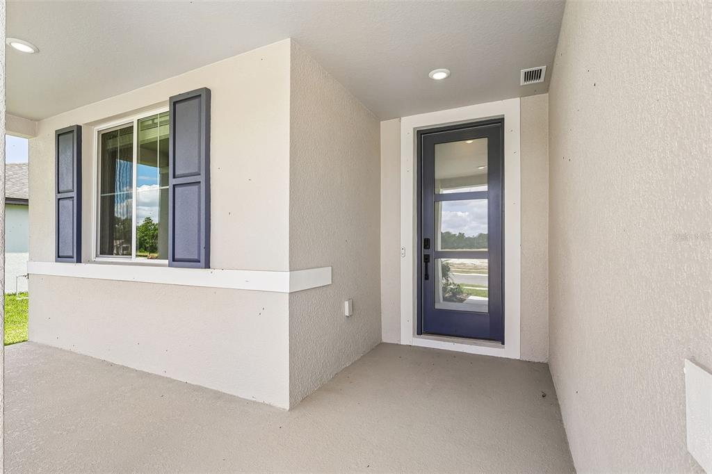 A covered front porch features a dark blue front door and a window with shutters — 3335 ORCHARD LOOP, BARTOW, FL
