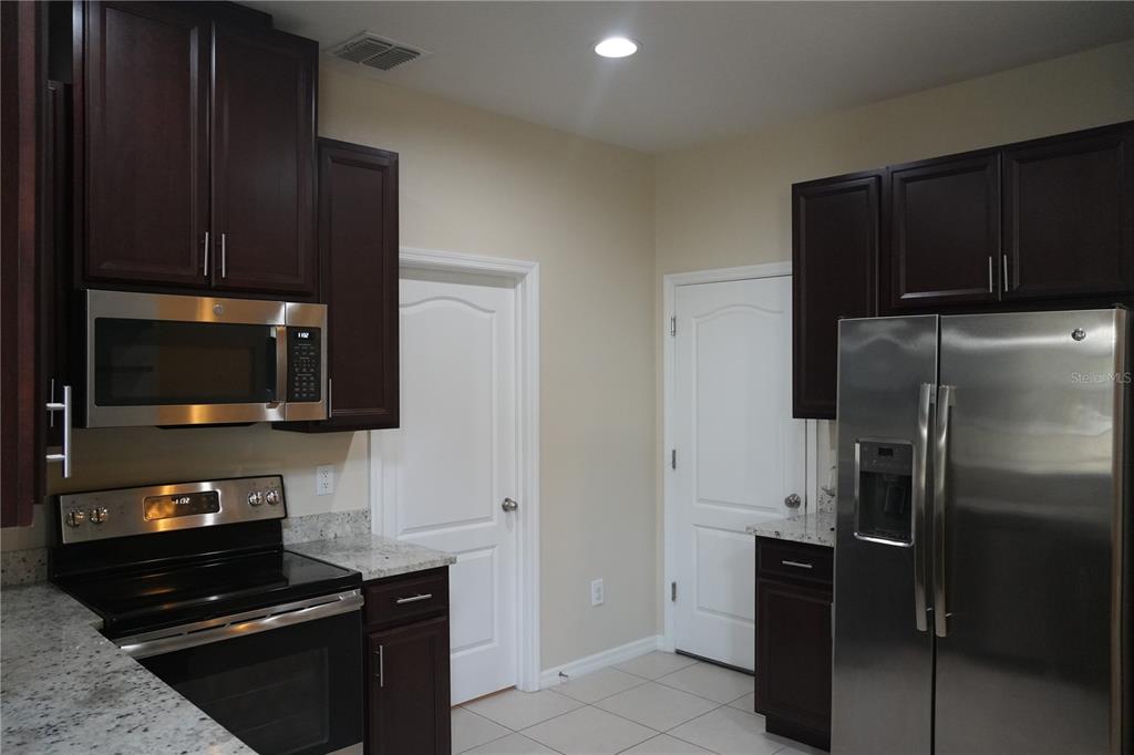 A kitchen features dark wood cabinets, stainless steel appliances, and granite countertops — 2212 LENNOX DALE LANE, BRANDON, FL