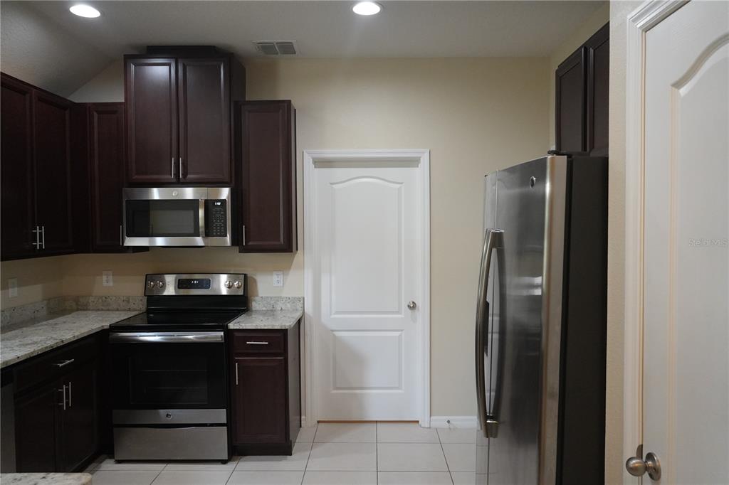 A kitchen features dark wood cabinets, stainless steel appliances, and light-colored granite countertops — 2212 LENNOX DALE LANE, BRANDON, FL