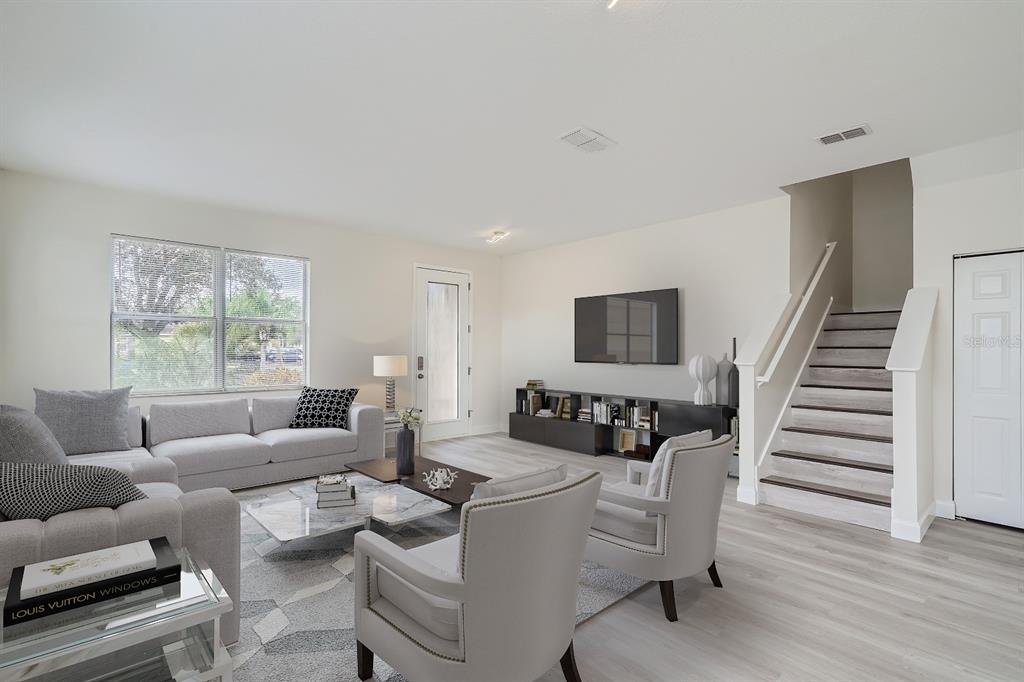 A living room features a grey sofa, two armchairs, a television, and a staircase — 5424 HAMMOCK VIEW LANE, APOLLO BEACH, FL