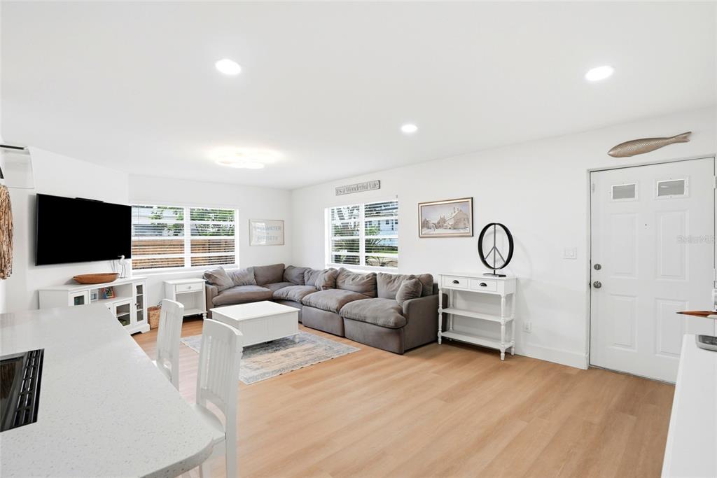 A bright living room features a gray sectional sofa, white furniture, and light wood flooring — 4027 HUNTINGTON STREET NE, ST PETERSBURG, FL