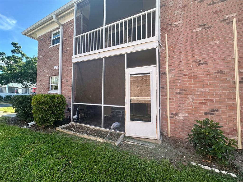 A brick building features a two-story screened-in porch with a white door and metal railings — 4115 34TH WAY S UNIT 194, ST PETERSBURG, FL